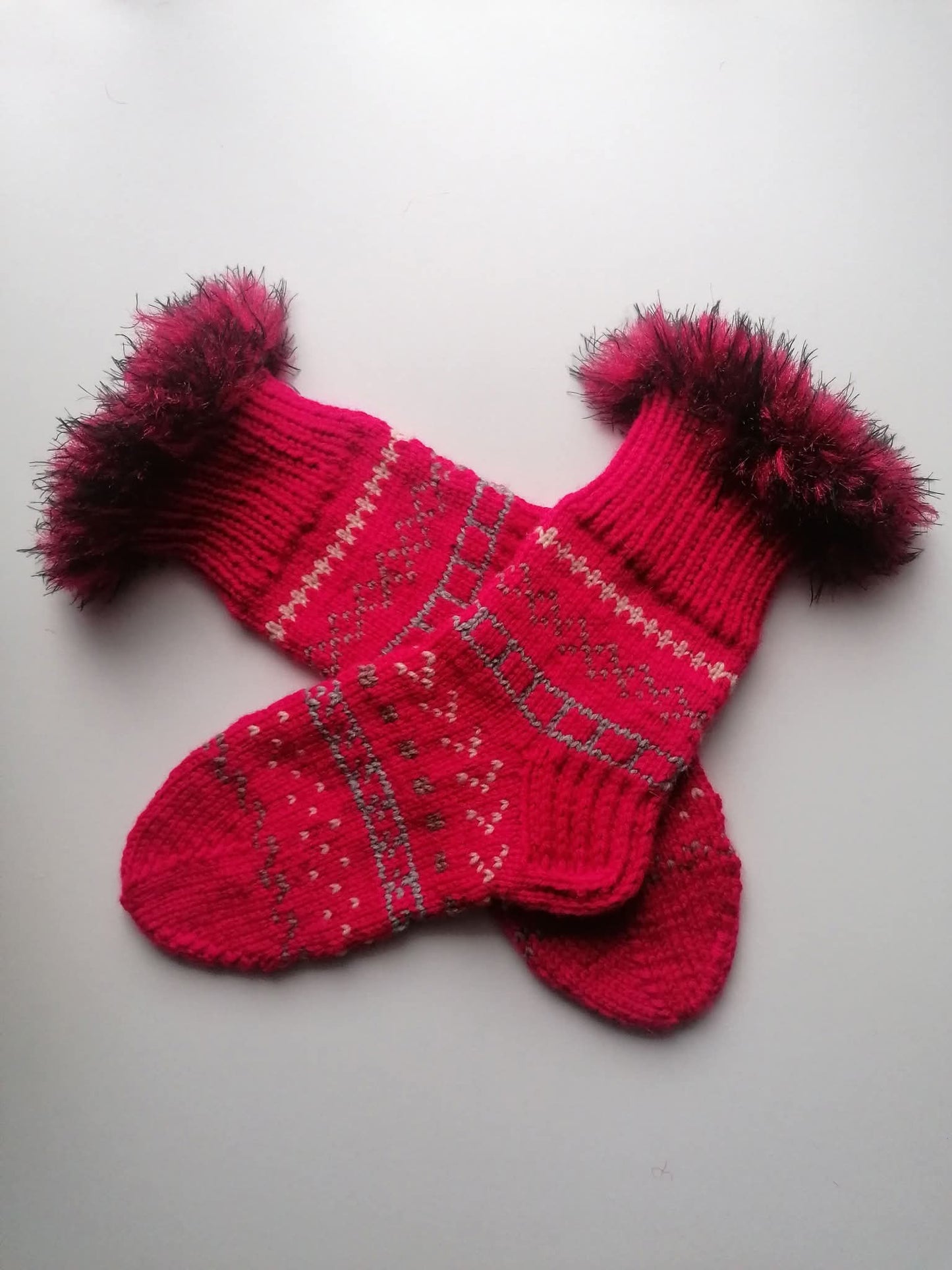 Pair of red fluffy knitted socks on a light gray background