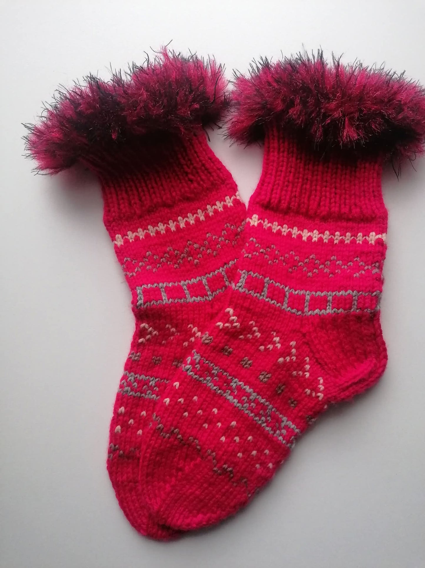 Pair of red fluffy knitted socks on a light gray background