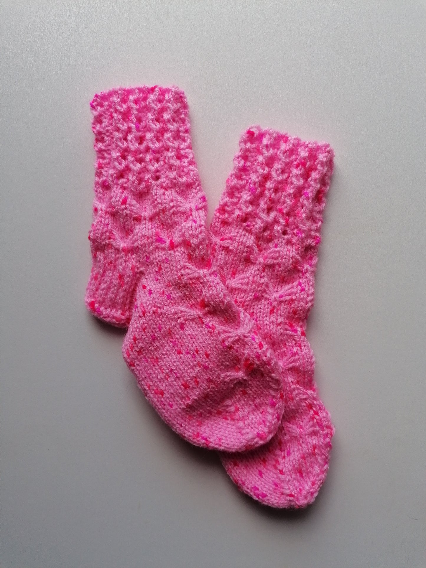 Pair of pink knitted socks on a gray background