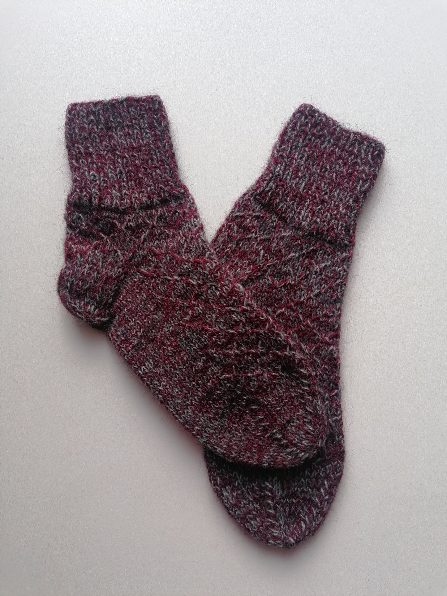 Pair of maroon and gray socks on a light gray background