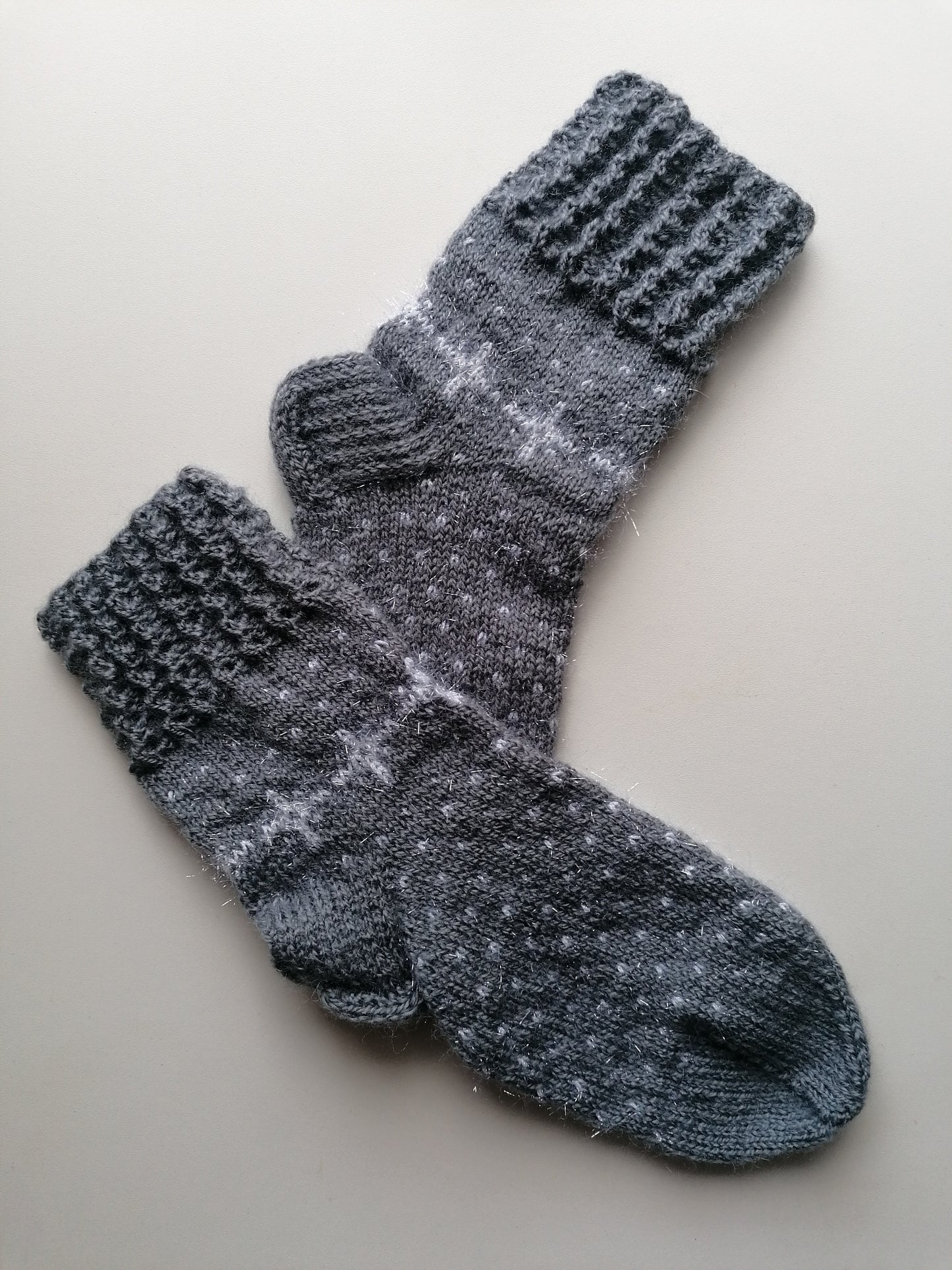 Pair of gray knitted socks on a light beige background