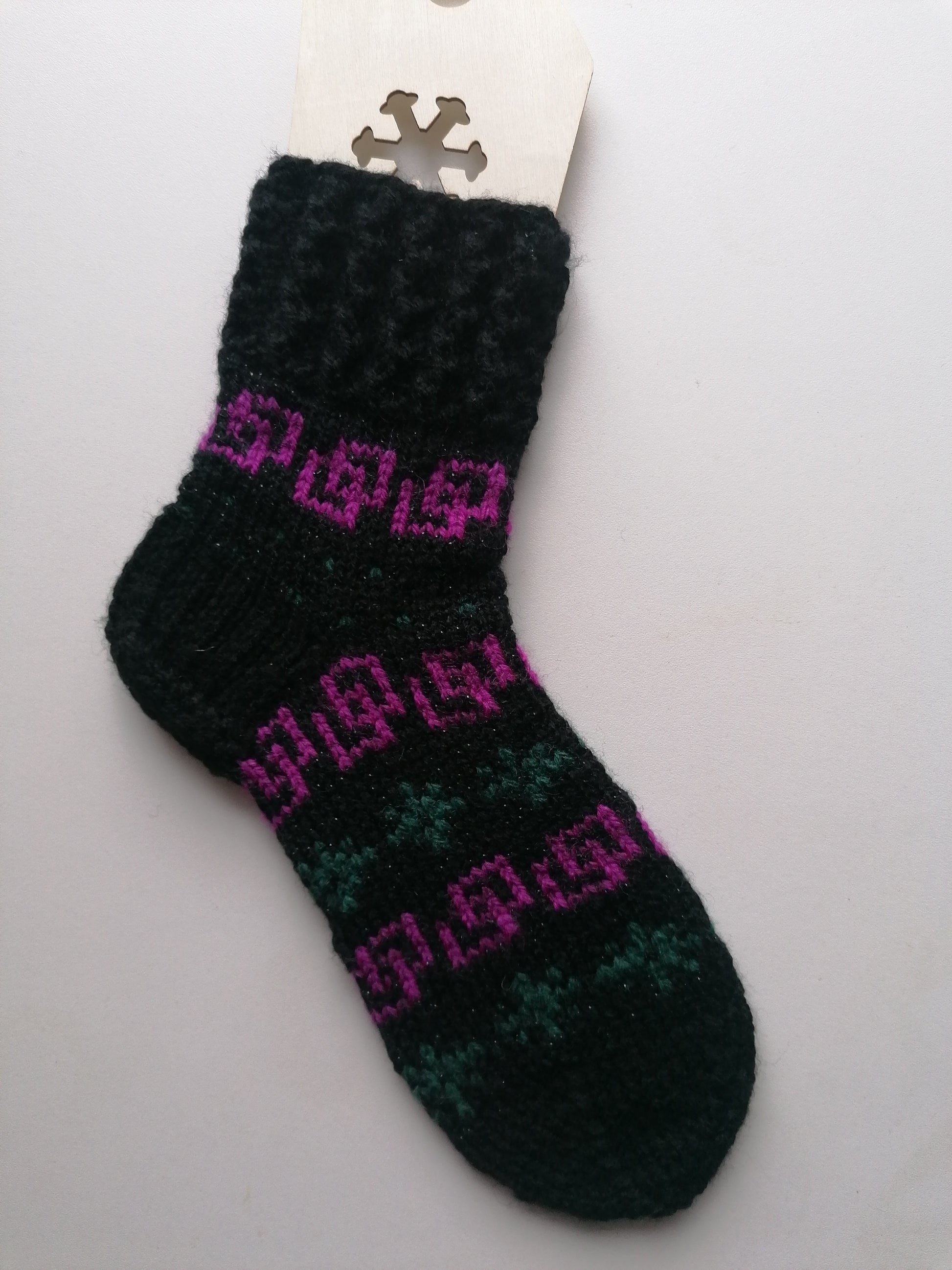 Black sock with pink and green pattern on a white background