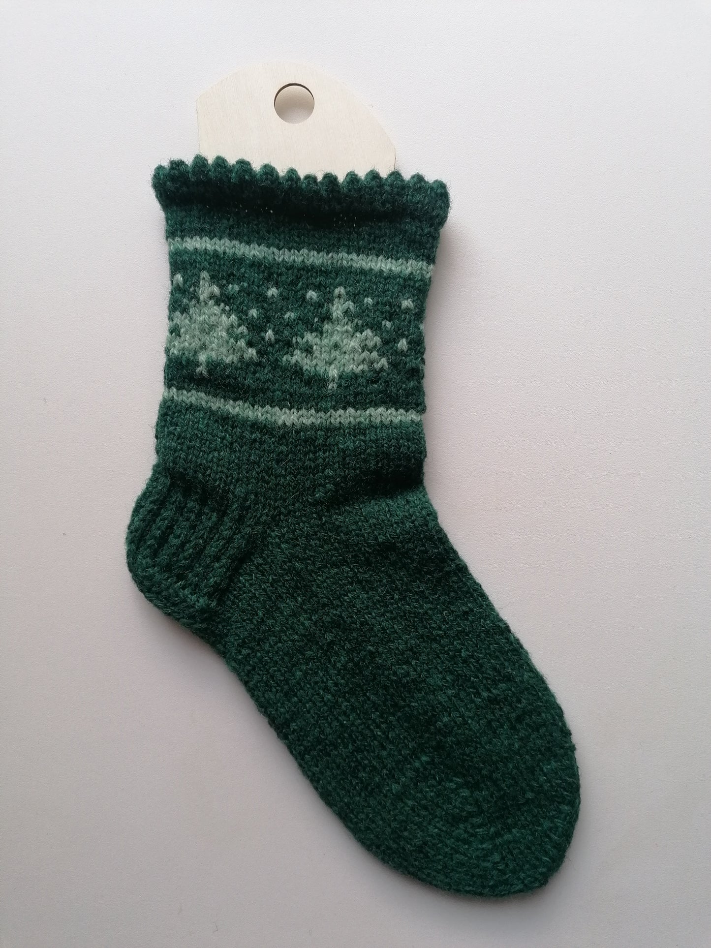 Green knitted sock with a tree pattern on a white background