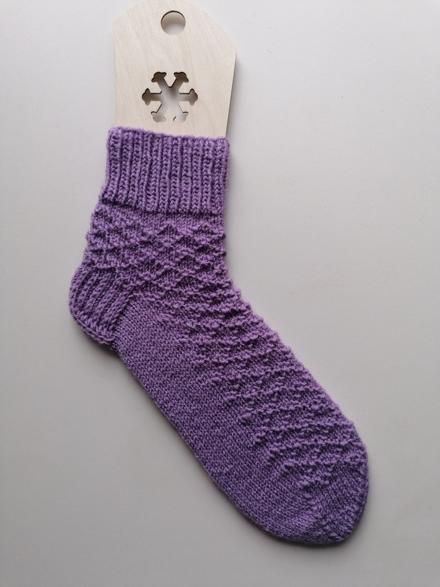 Purple knitted sock on a gray background