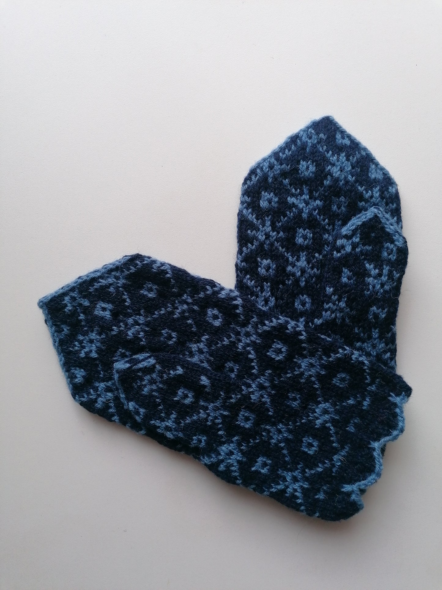 Pair of blue knitted socks with a pattern on a white background