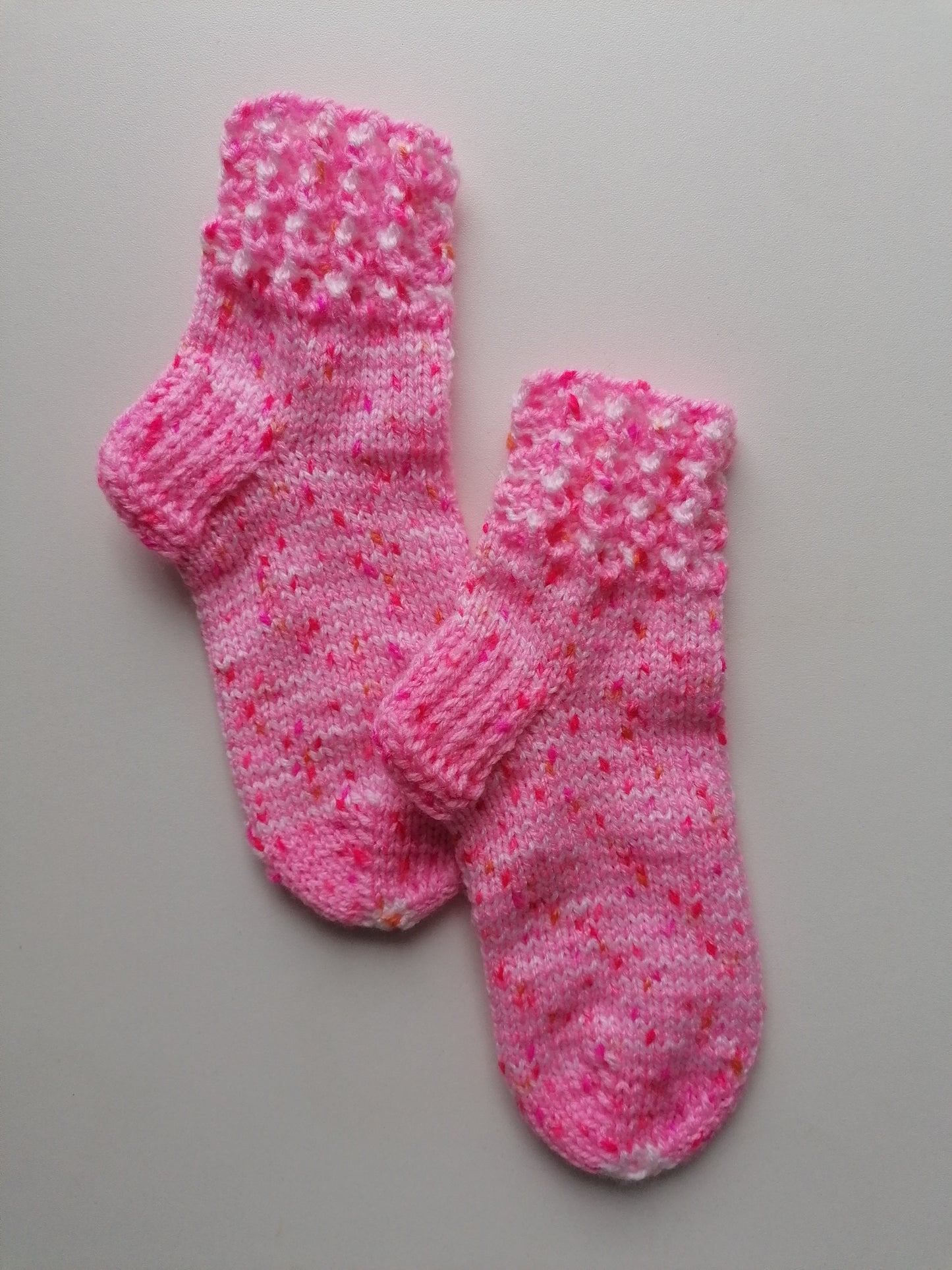Pair of pink knitted socks on a gray background