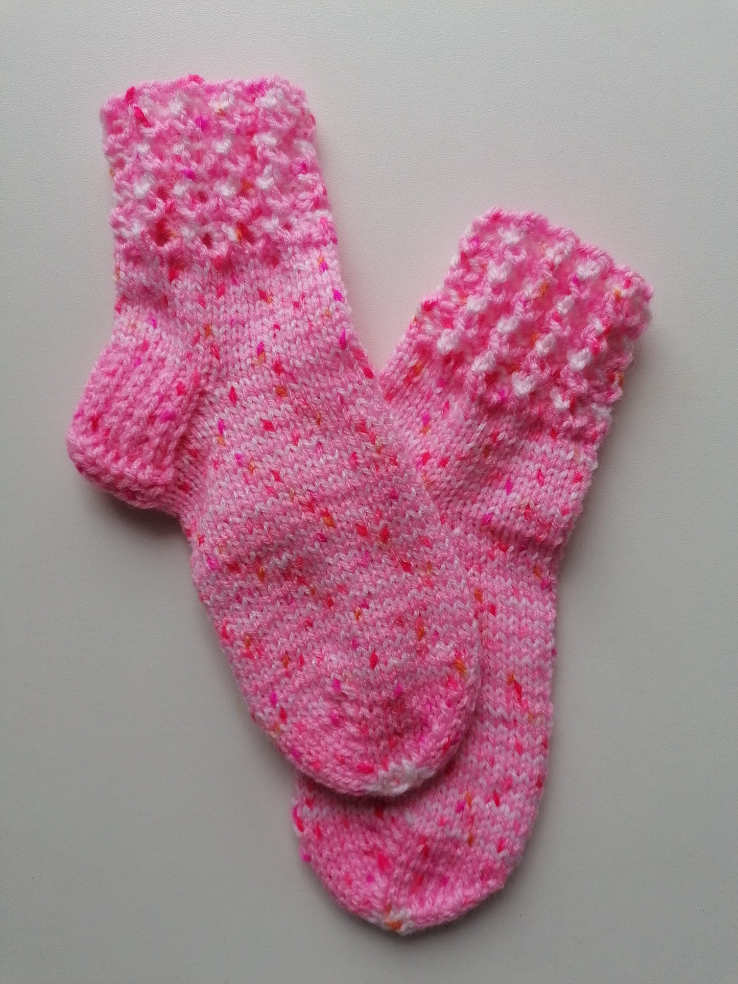 Pair of pink knitted socks on a gray background