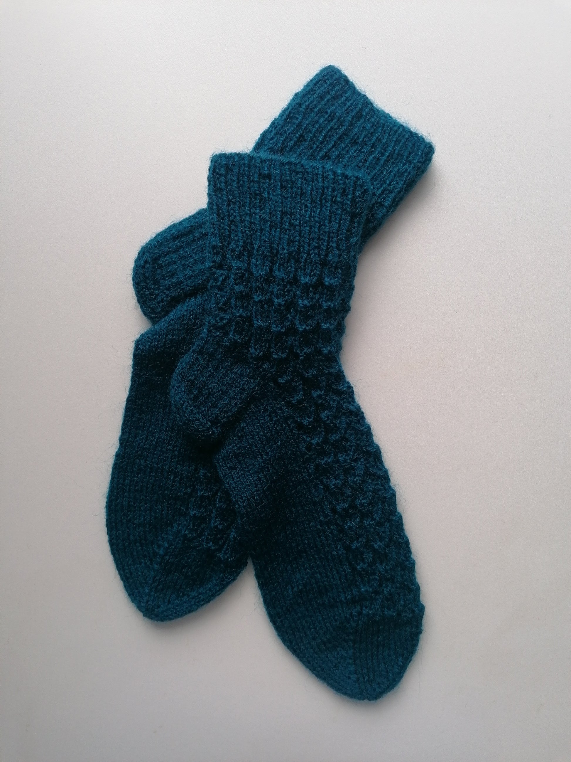 Pair of blue knitted socks on a light gray background