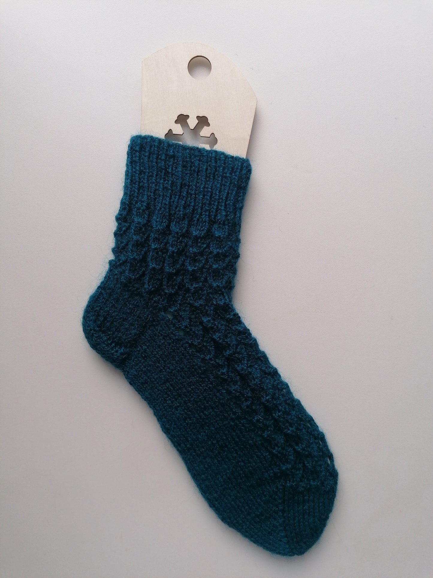 Teal knitted sock on a white background
