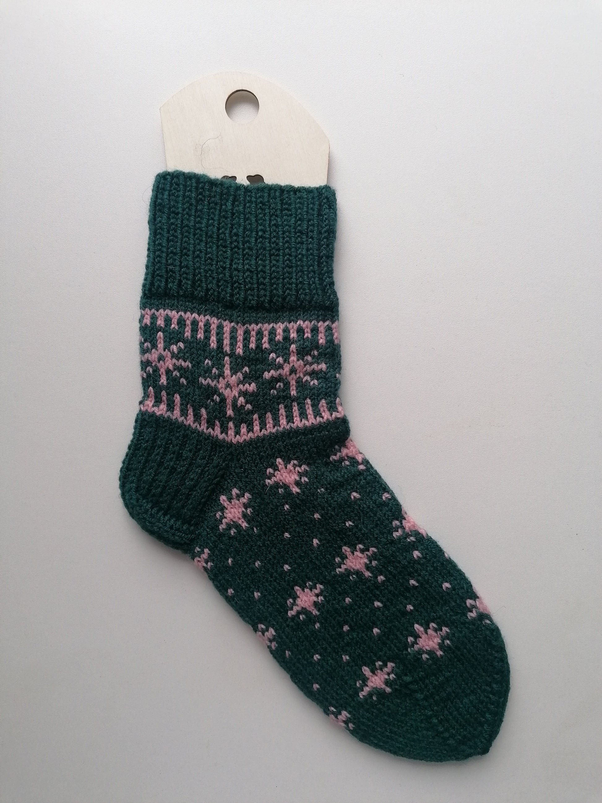 Green knitted sock with pink patterns on a white background