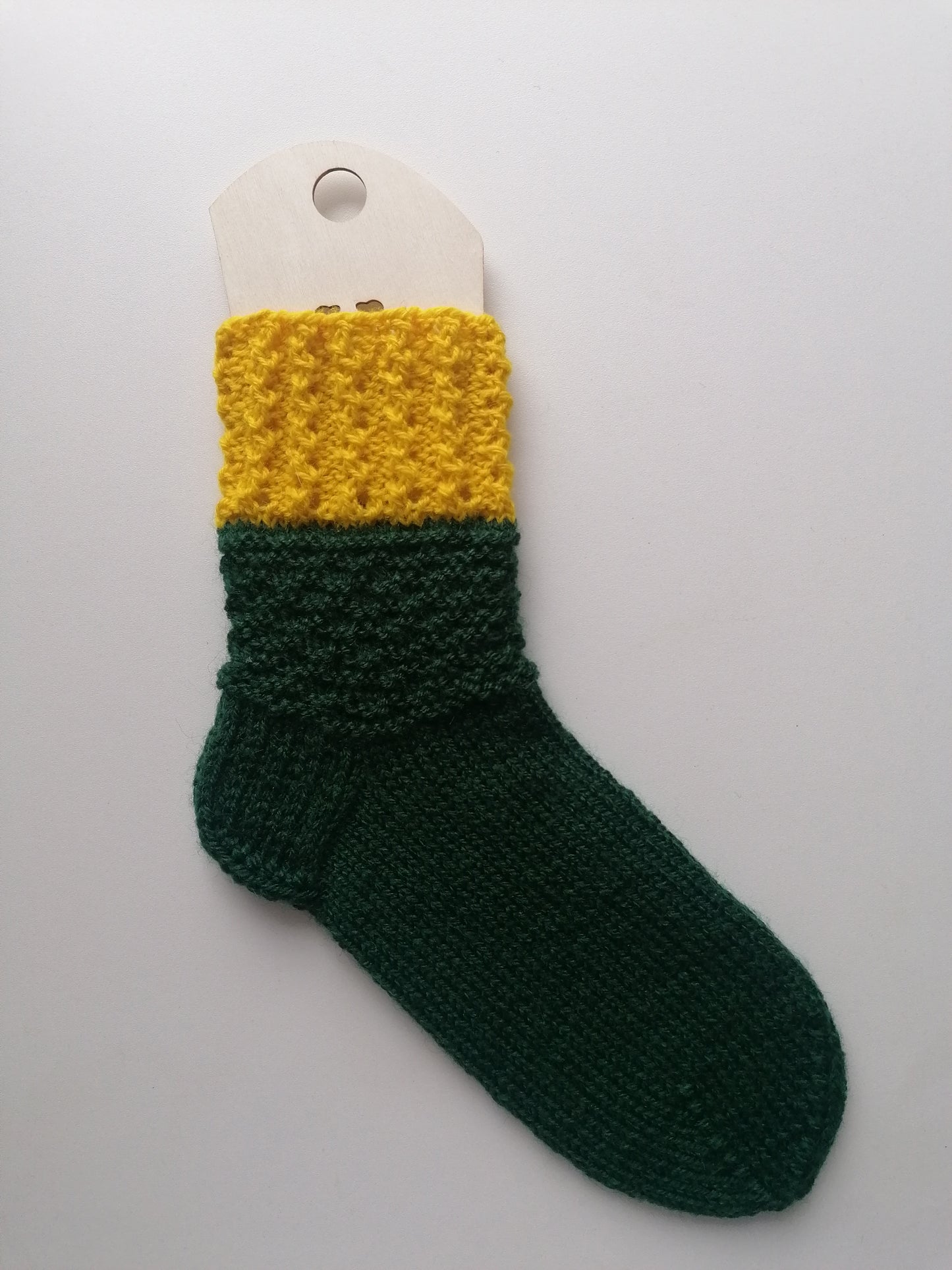 Green and yellow knitted sock on a white background