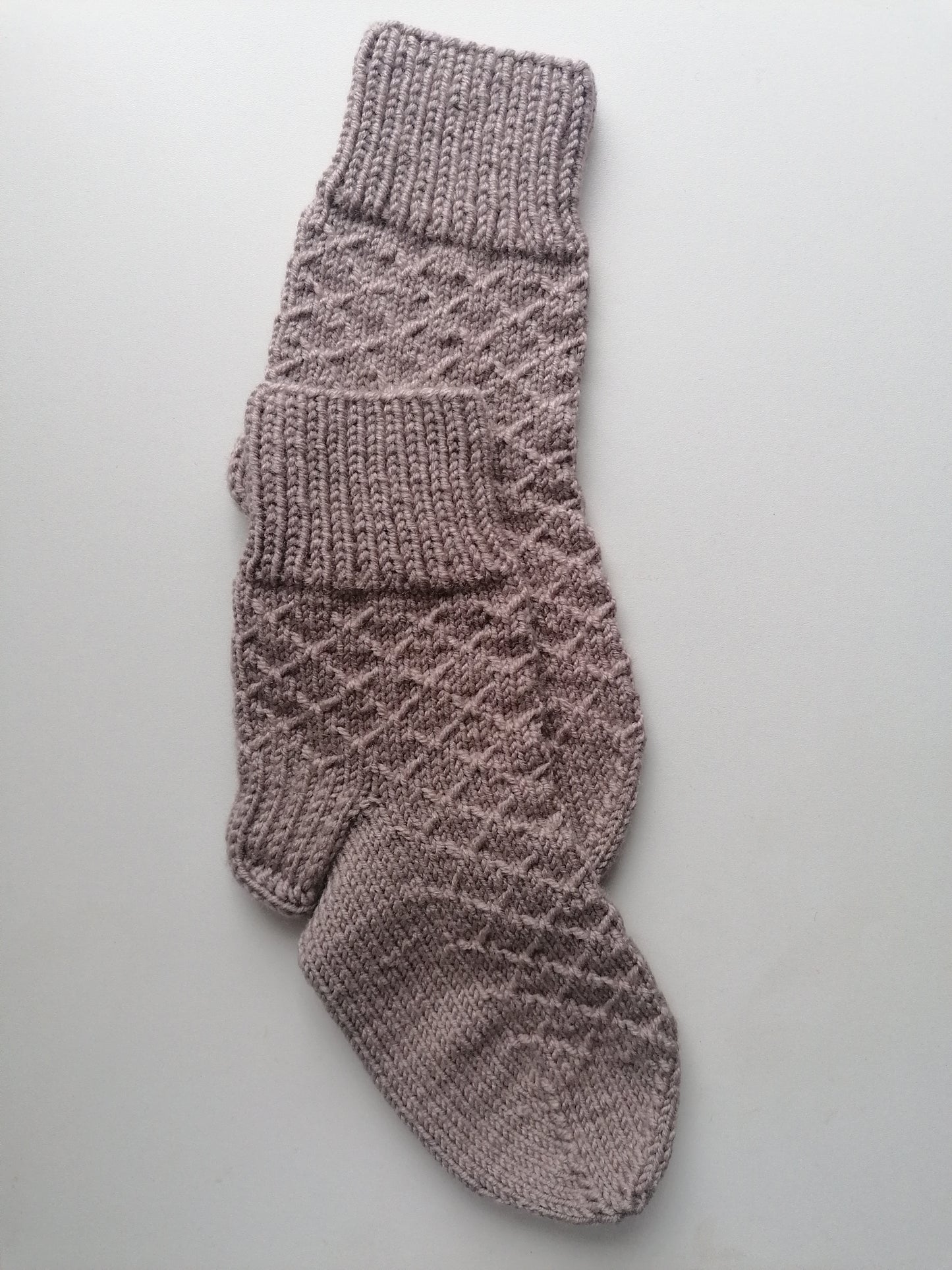 Knitted sock with a diamond pattern on a light gray background