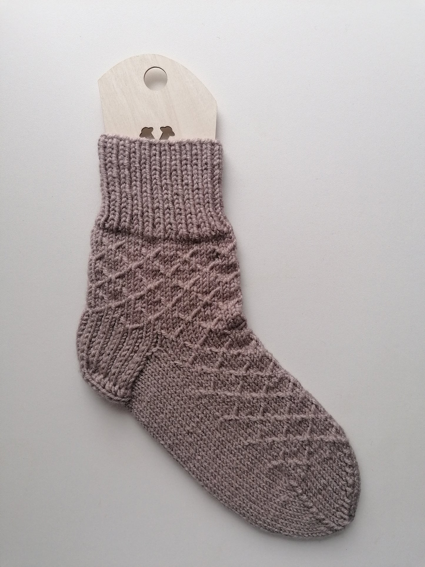 Beige knitted sock on a gray background