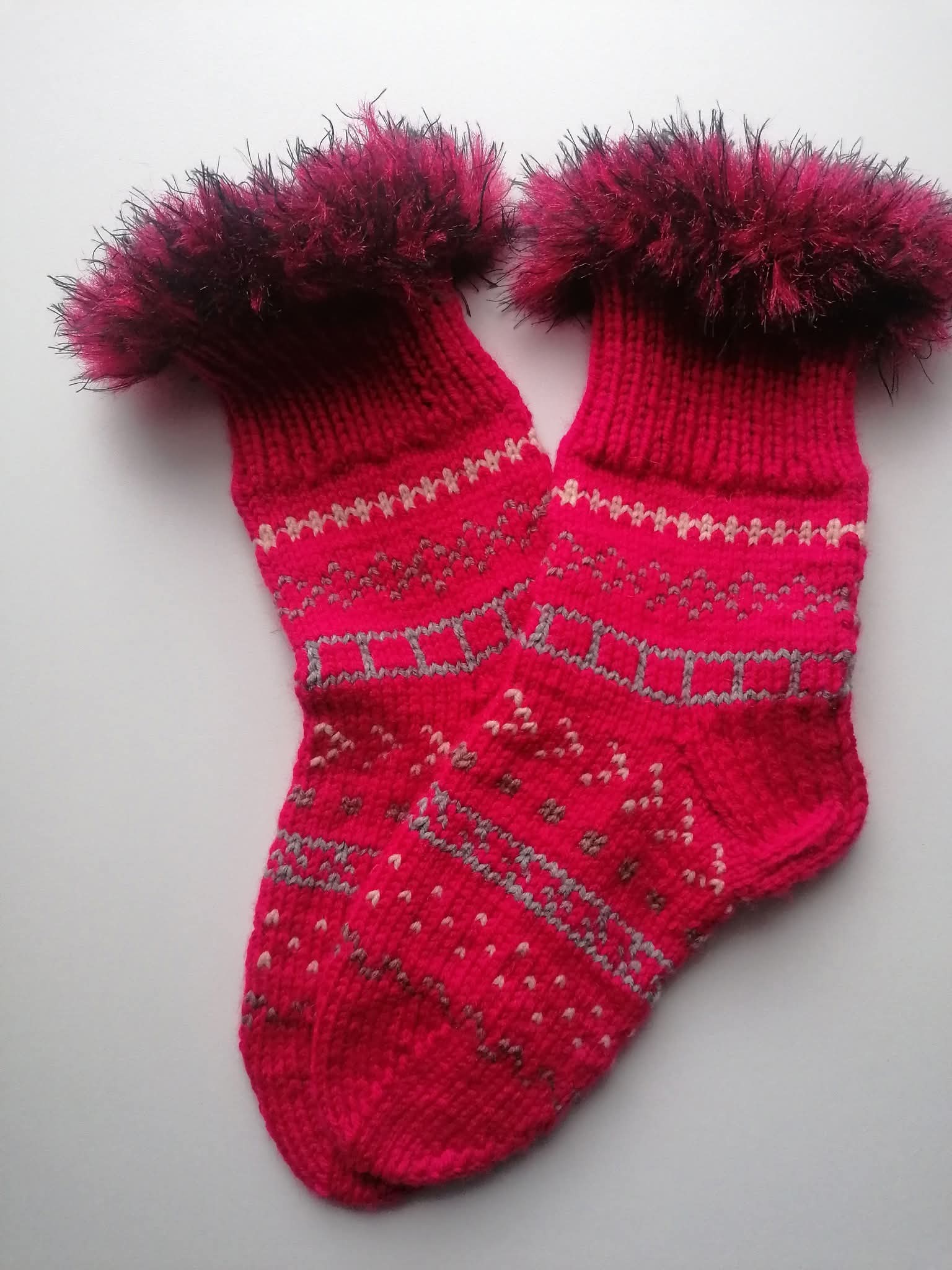 Pair of red fluffy knitted socks on a light gray background