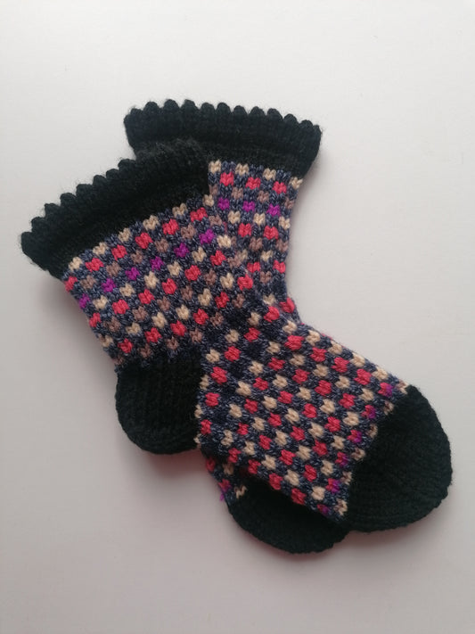 Pair of patterned socks with black cuffs and toes on a light background