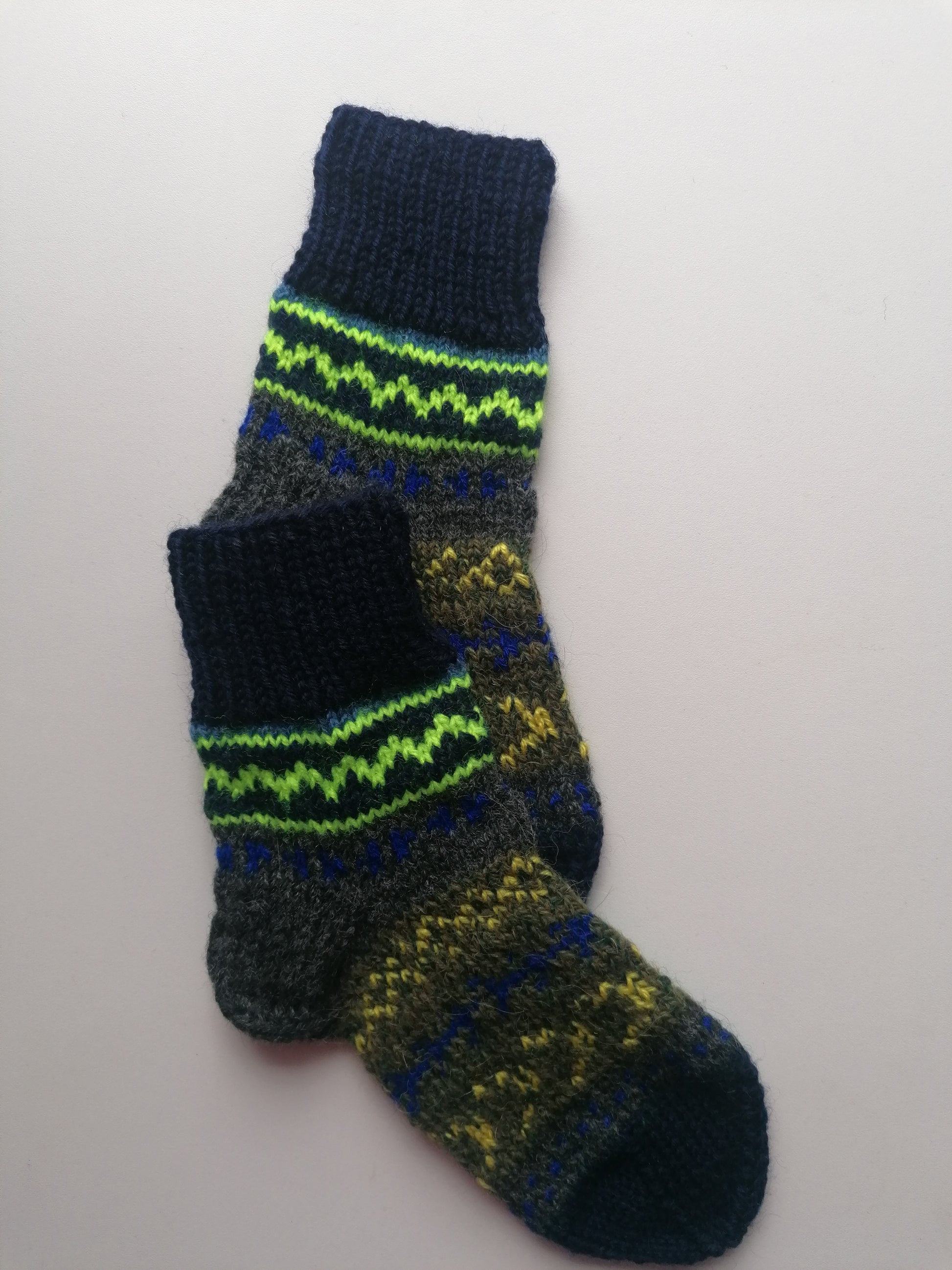 Knitted sock with green and blue pattern on a white background