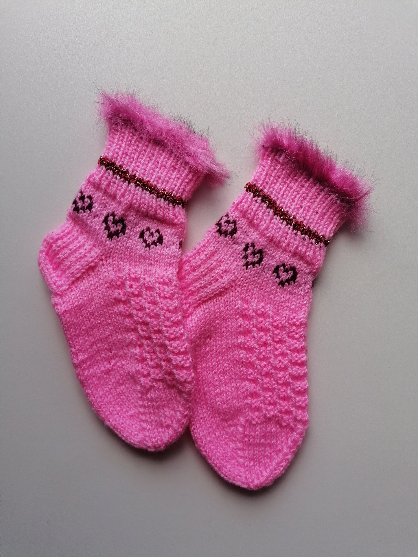 Pair of pink knitted socks with decorative patterns on a light gray background