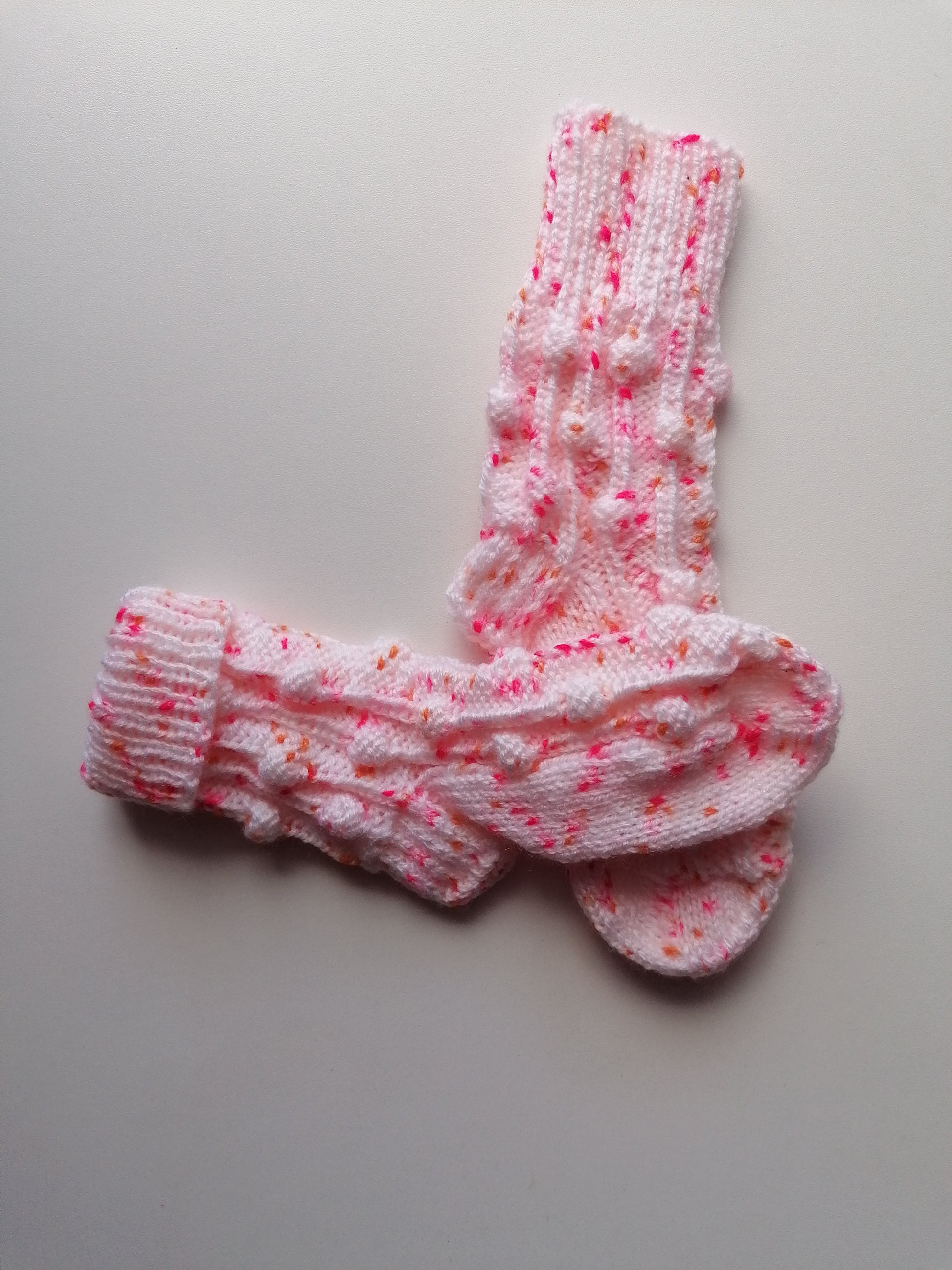 Pair of pink socks with white pattern on a light gray background