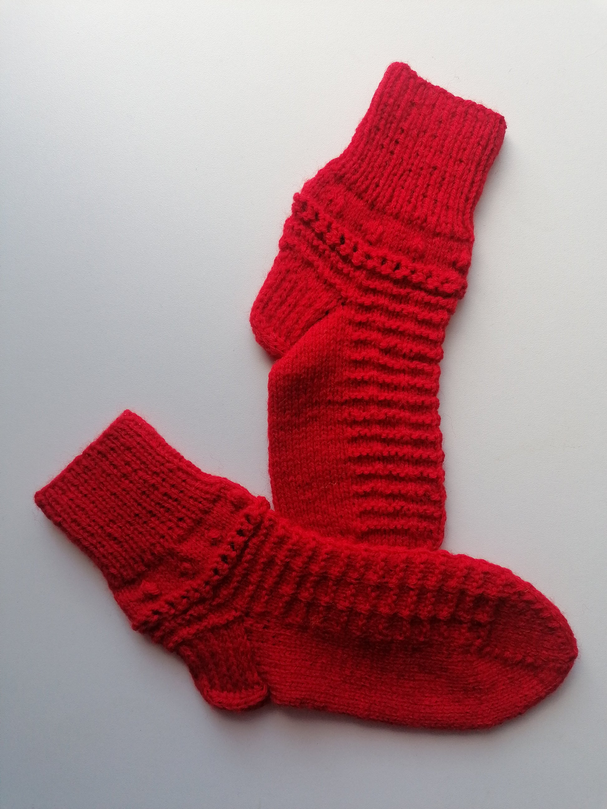 Pair of red knitted socks on a light gray background