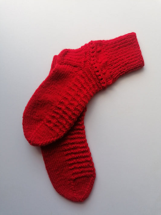 Pair of red knitted socks on a light gray background
