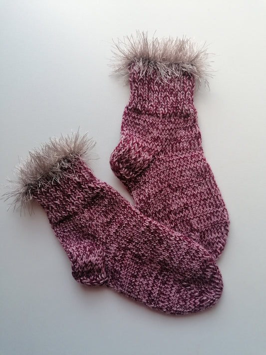 Pair of knitted socks with fur cuffs on a white background