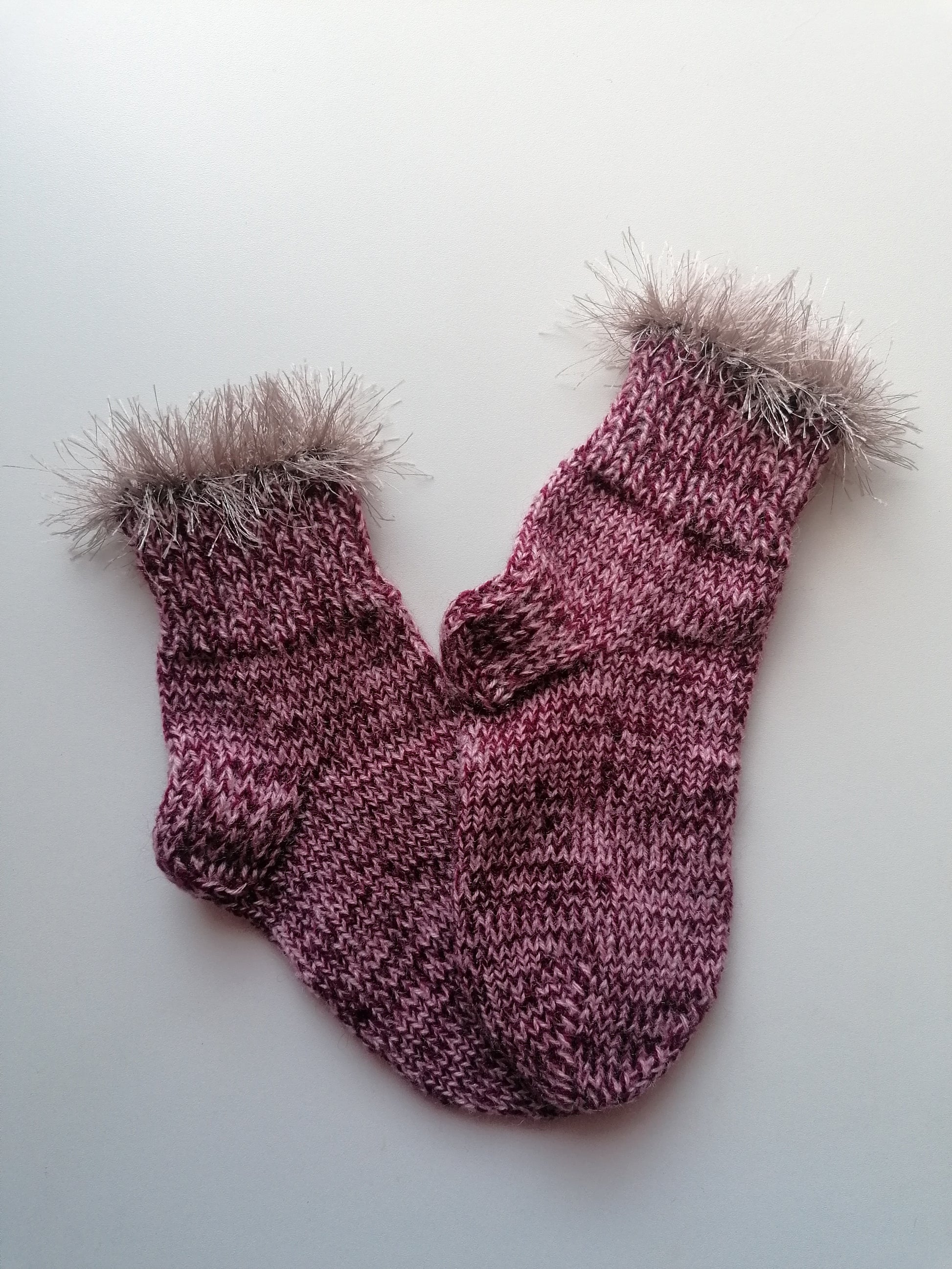 Pair of knitted socks with fur cuffs on a white background