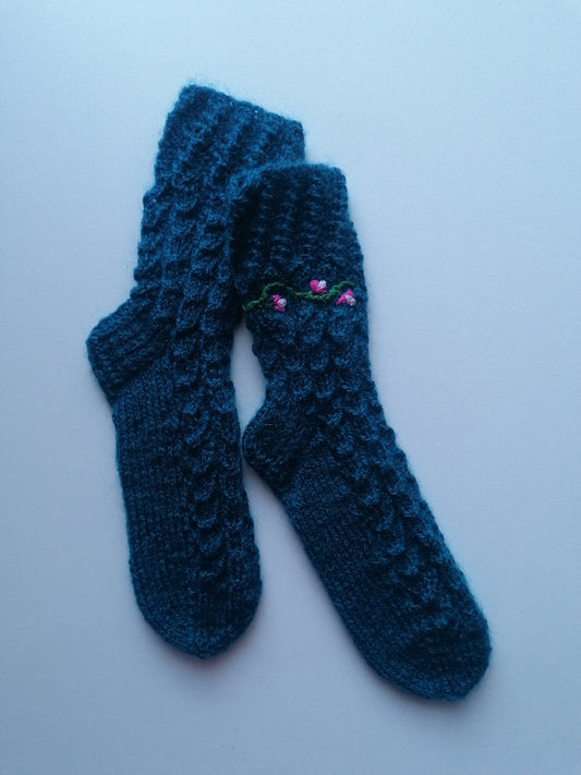 Pair of blue knitted socks with a floral design on a white background