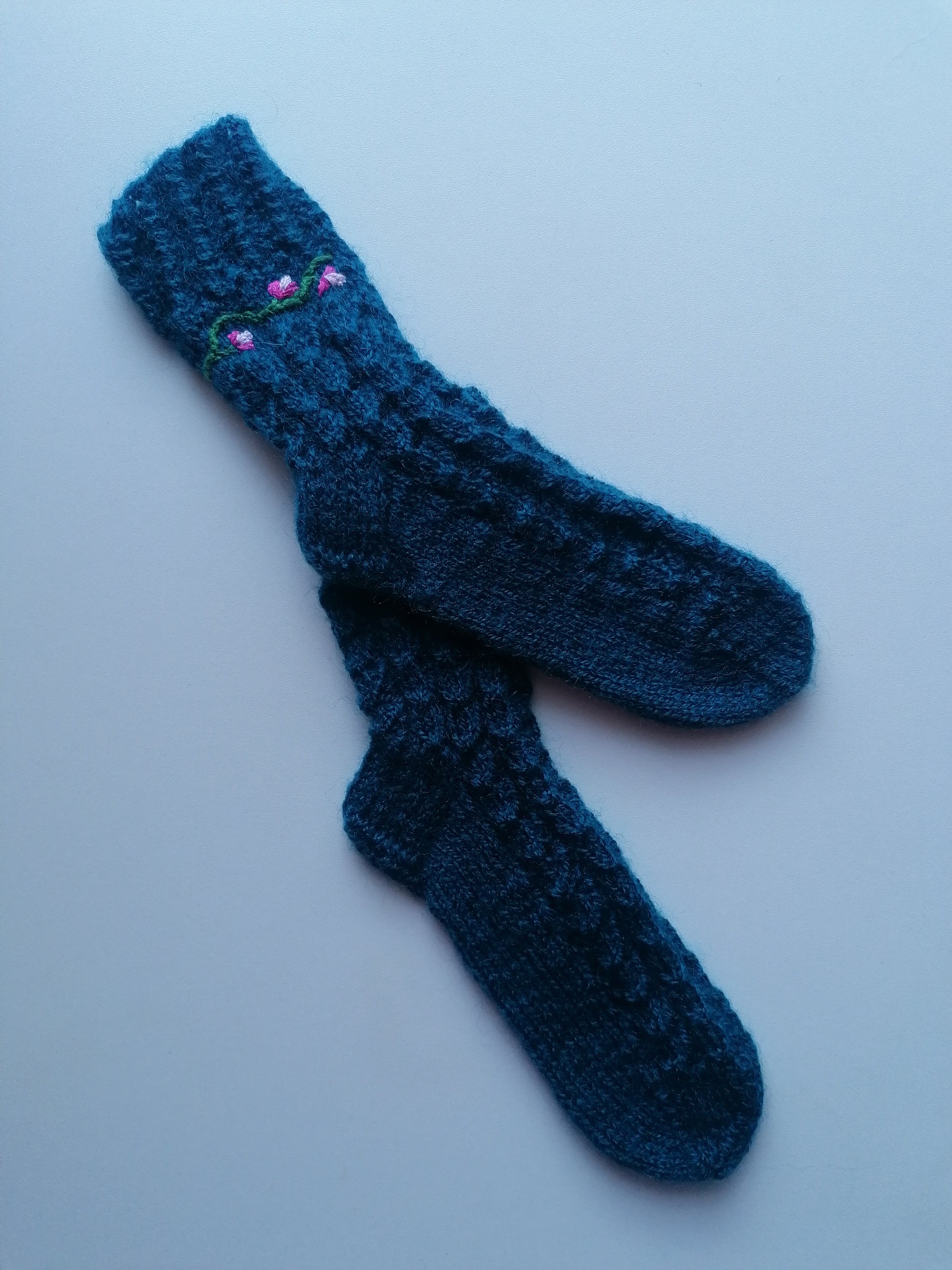 Pair of blue knitted socks on a light gray background