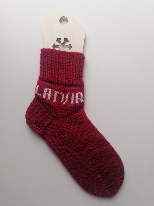 Red baby sock with white text Latvia on a white background