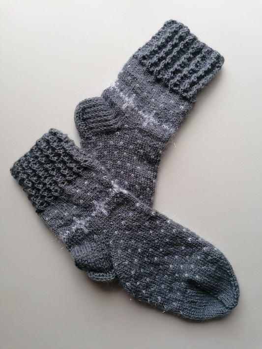 Pair of gray knitted socks on a light beige background