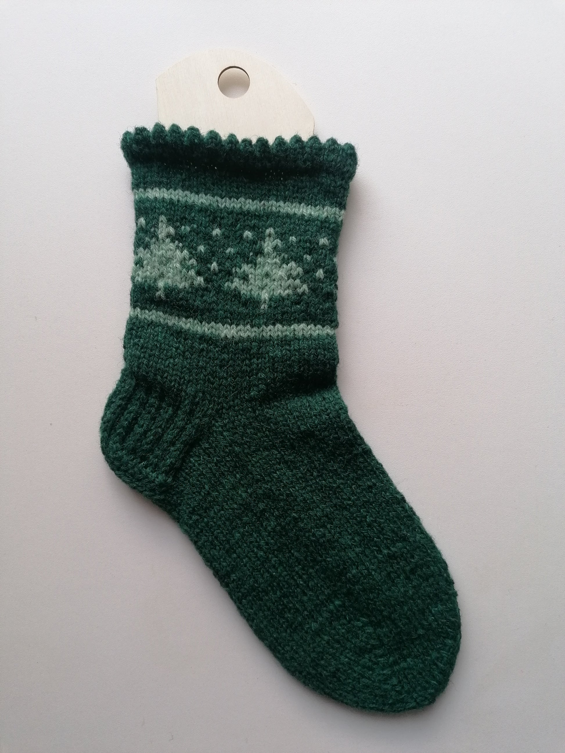 Green knitted sock with a tree pattern on a white background