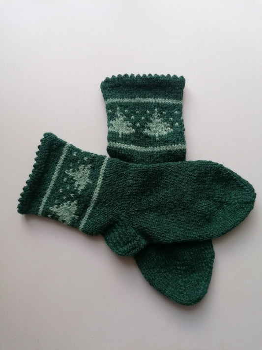 Pair of green knitted socks with a tree pattern on a light gray background