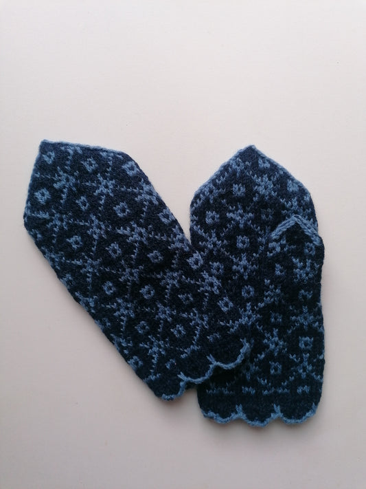 Pair of blue knitted mittens with a pattern on a light gray background