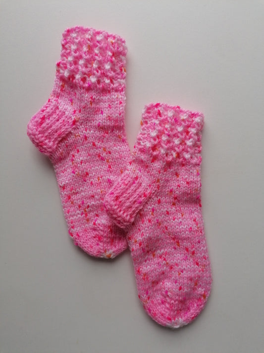 Pair of pink knitted socks on a gray background