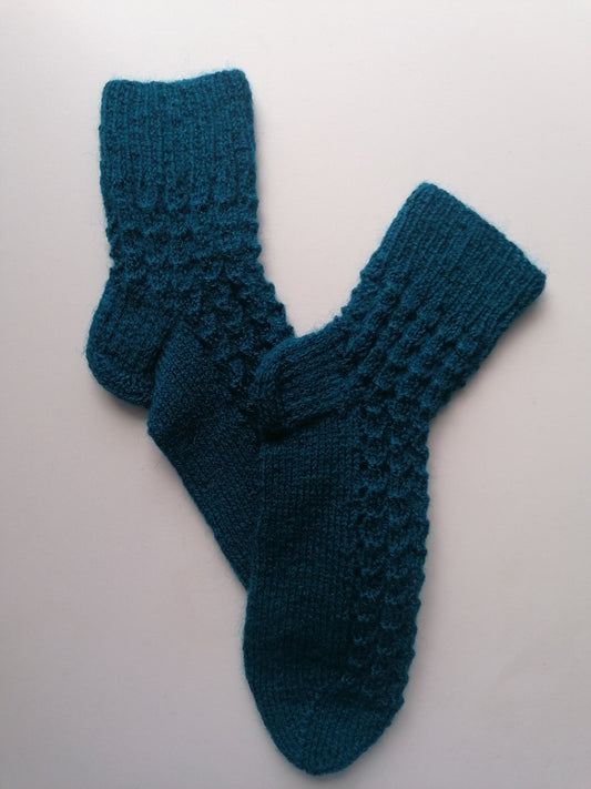 Pair of teal knitted socks on a light gray background