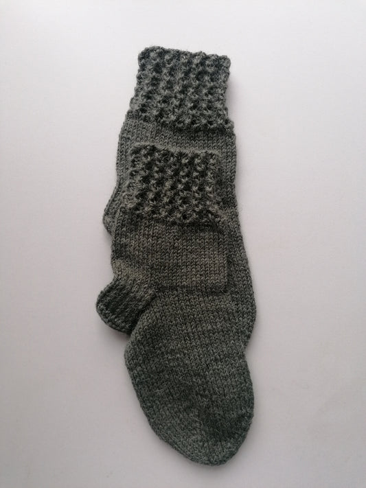 Green knitted socks on a light gray background