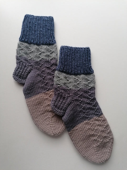 Pair of knitted socks with a gradient color pattern on a light gray background