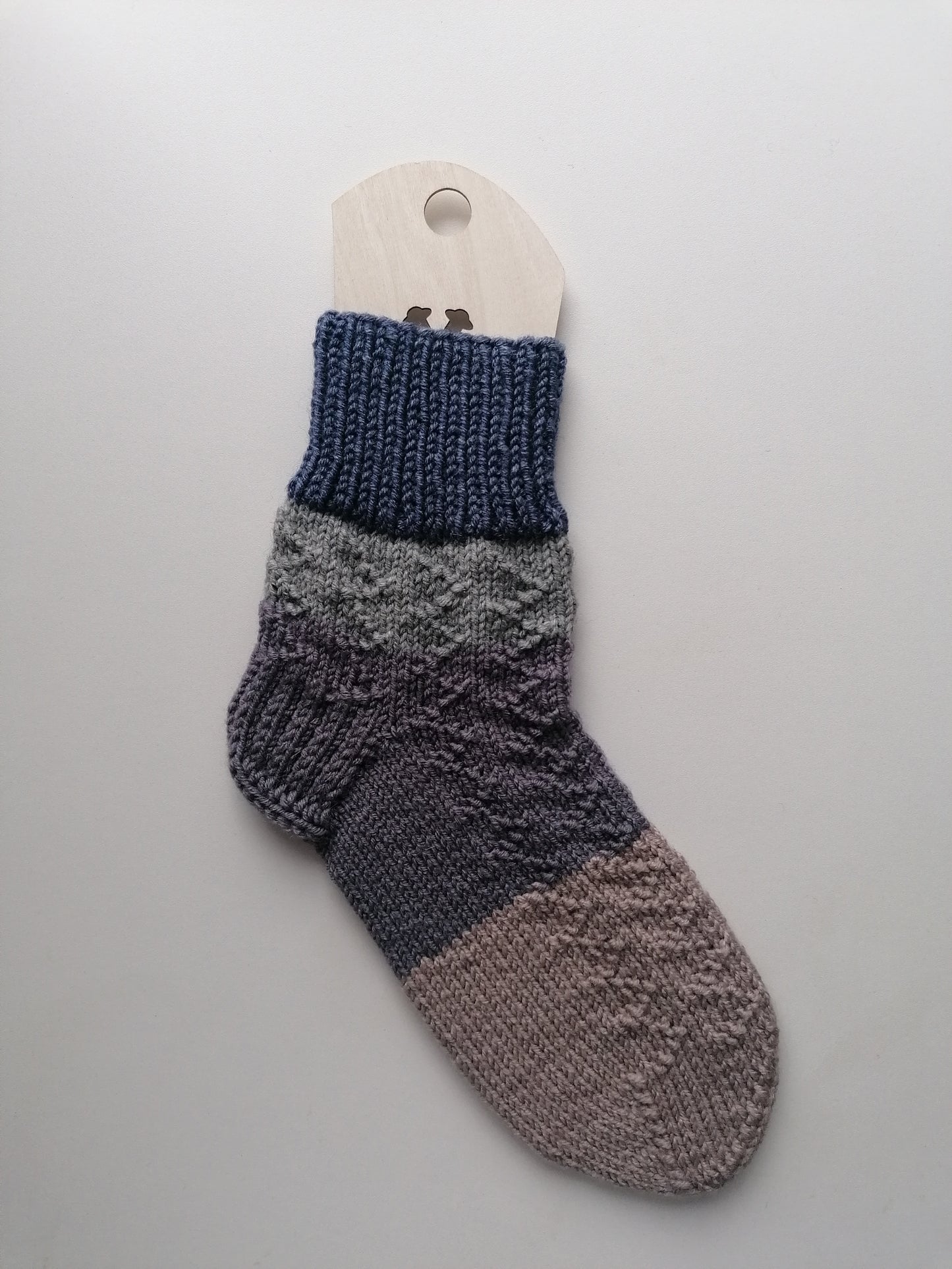 Knitted sock with gradient color pattern on a gray background