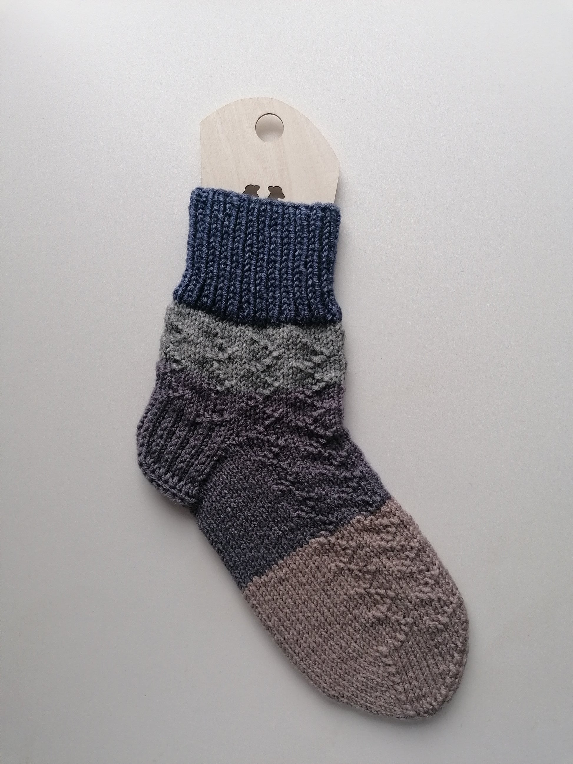 Knitted sock with gradient color pattern on a gray background