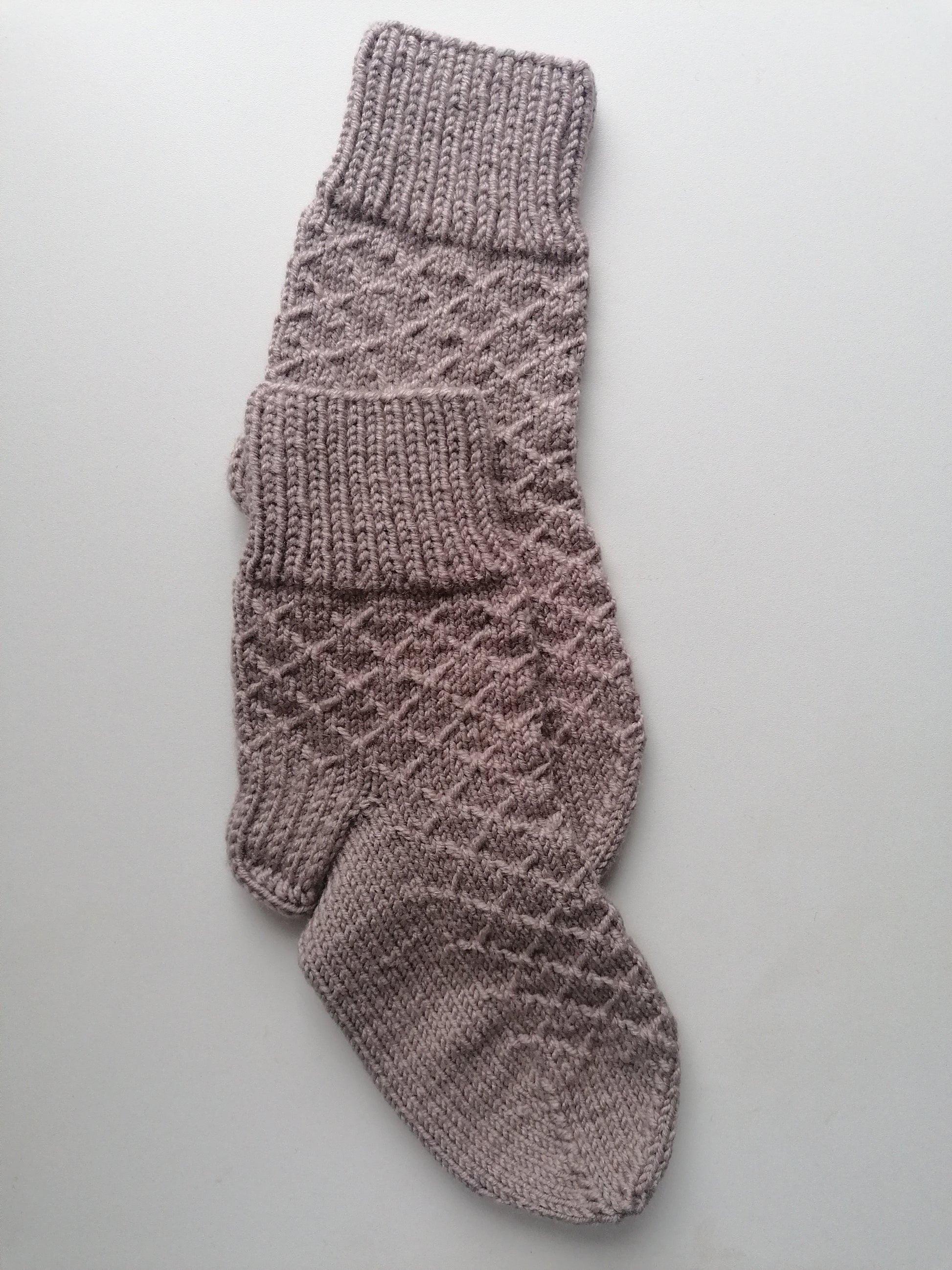 Knitted sock with a diamond pattern on a light gray background