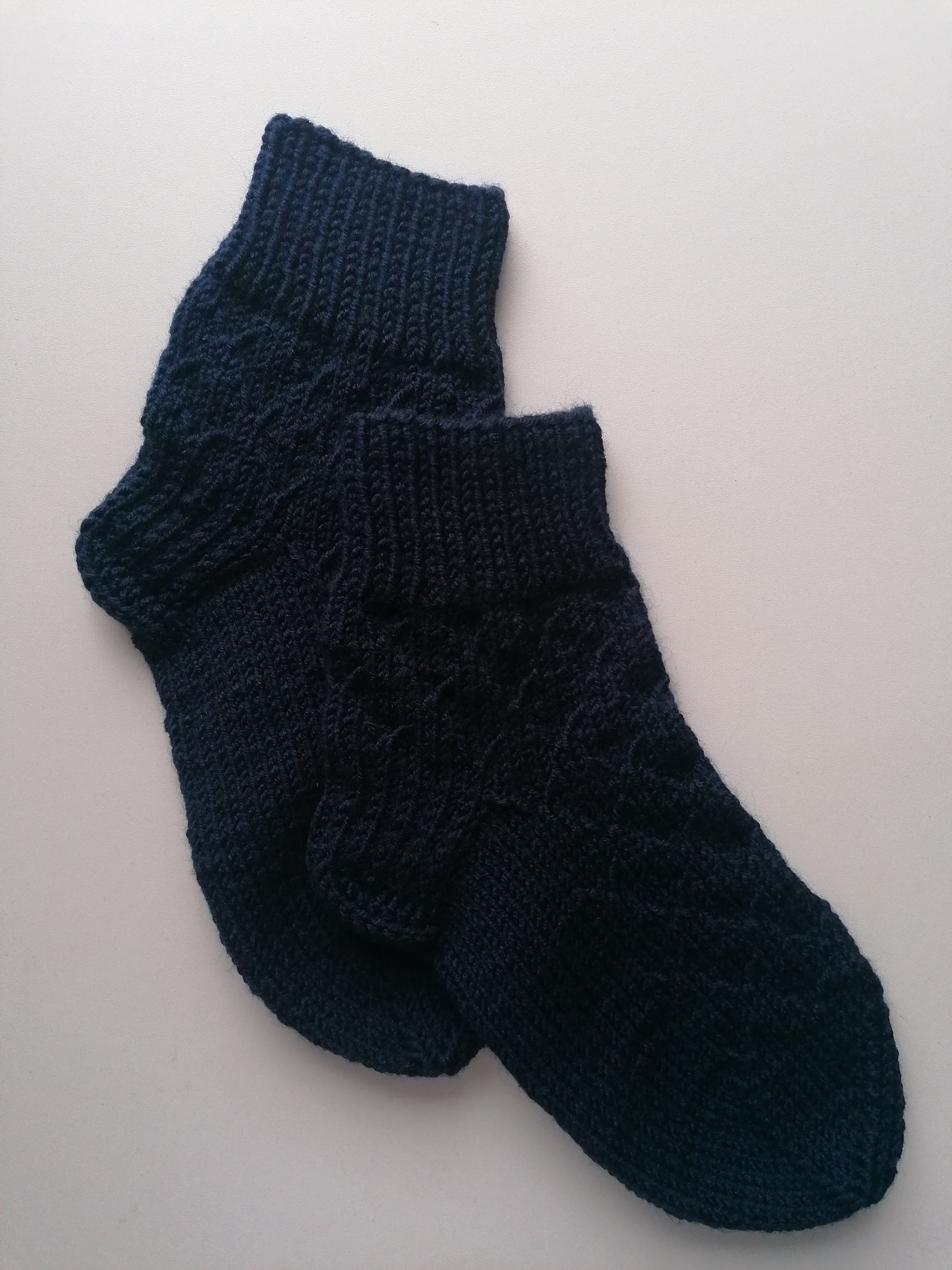 Pair of dark blue knitted socks on a light gray background