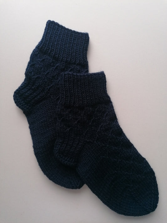 Pair of dark blue knitted socks on a light gray background